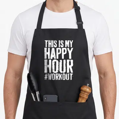 Workout hour apron - White distressed text reading THIS IS MY HAPPY HOUR #WORKOUT stacked vertically — shown on a black cotton canvas apron against a white background