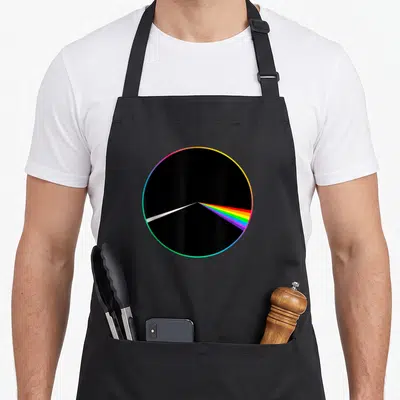 70s vinyl apron - Black circle with white beam splitting into rainbow spectrum light refraction — shown on a black cotton canvas apron against a white background