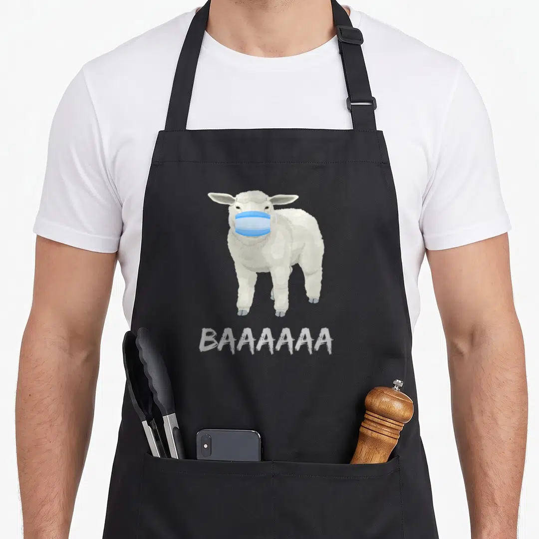 Anti sheep apron - White cartoon sheep wearing blue surgical mask with BAAAAAAA text printed below — shown on a black cotton canvas apron against a white background