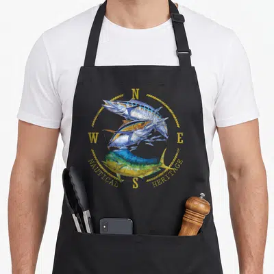 Mahi fish apron - Three stacked fish inside compass rose with Nautical Heritage text in blue and yellow — shown on a black cotton canvas apron against a white background