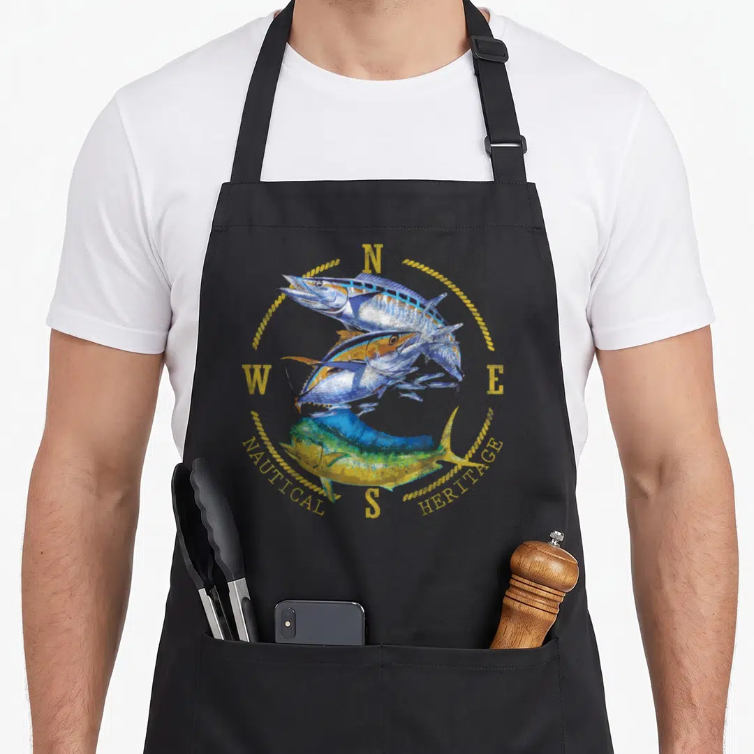 Mahi fish apron - Three stacked fish inside compass rose with Nautical Heritage text in blue and yellow — shown on a black cotton canvas apron against a white background