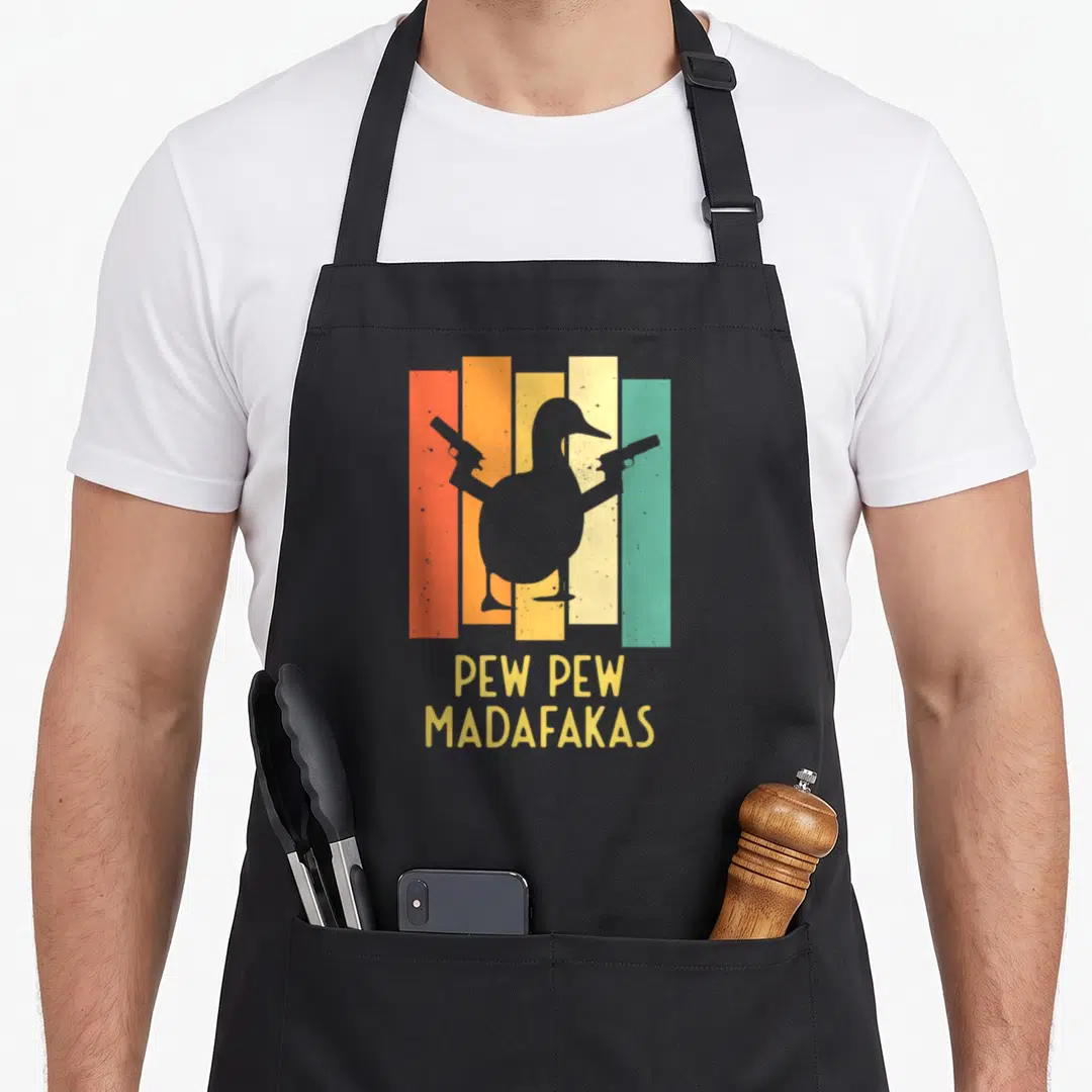 Pistol cotton duck aprons - Grey duck silhouette holding two guns over orange, yellow, teal, and grey stripes with text — shown on a black cotton canvas apron against a white background