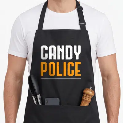 Candy police halloween apron - Stacked CANDY POLICE text in white and orange with a white horizontal line underneath — shown on a black cotton canvas apron against a white background