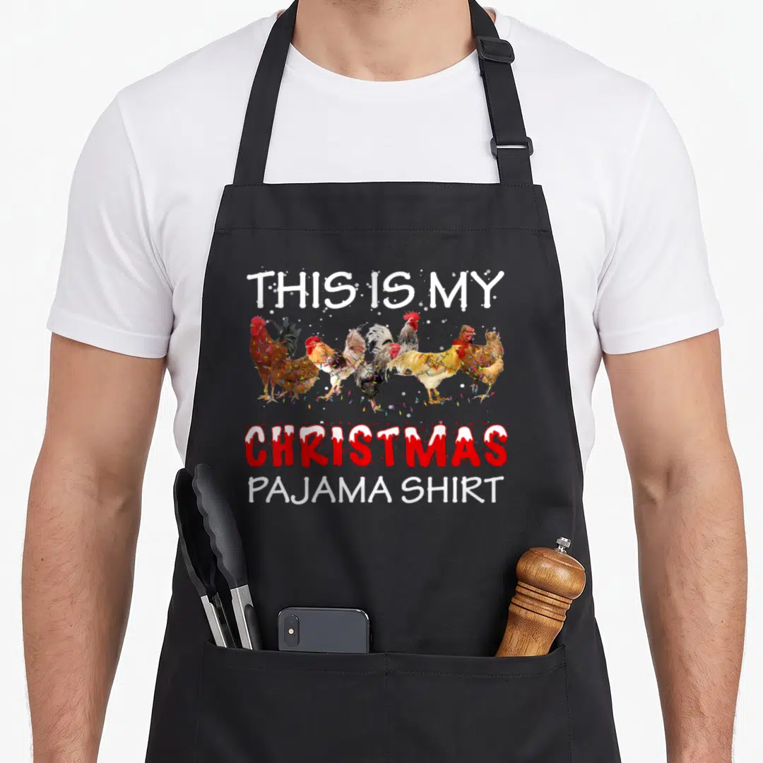Chicken pajama family christmas aprons - Six roosters wrapped in Christmas lights under text reading THIS IS MY — shown on a black cotton canvas apron against a white background