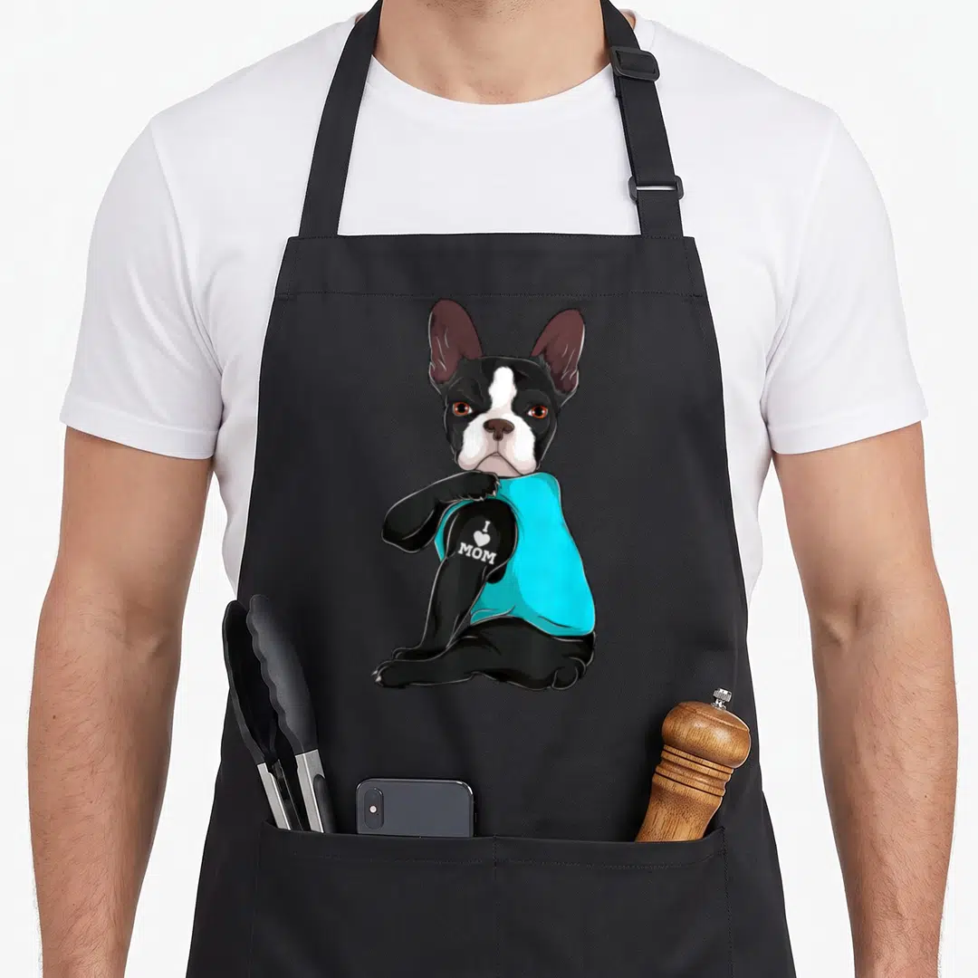 Boston terrier mom apron - Cartoon dog in cyan shirt with I Love Mom text on arm — shown on a black cotton canvas apron against a white background