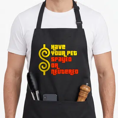 Spayed pet apron - Yellow dollar sign and red text reading HAVE YOUR PET SPAYED OR NEUTERED on black background — shown on a black cotton canvas apron against a white background