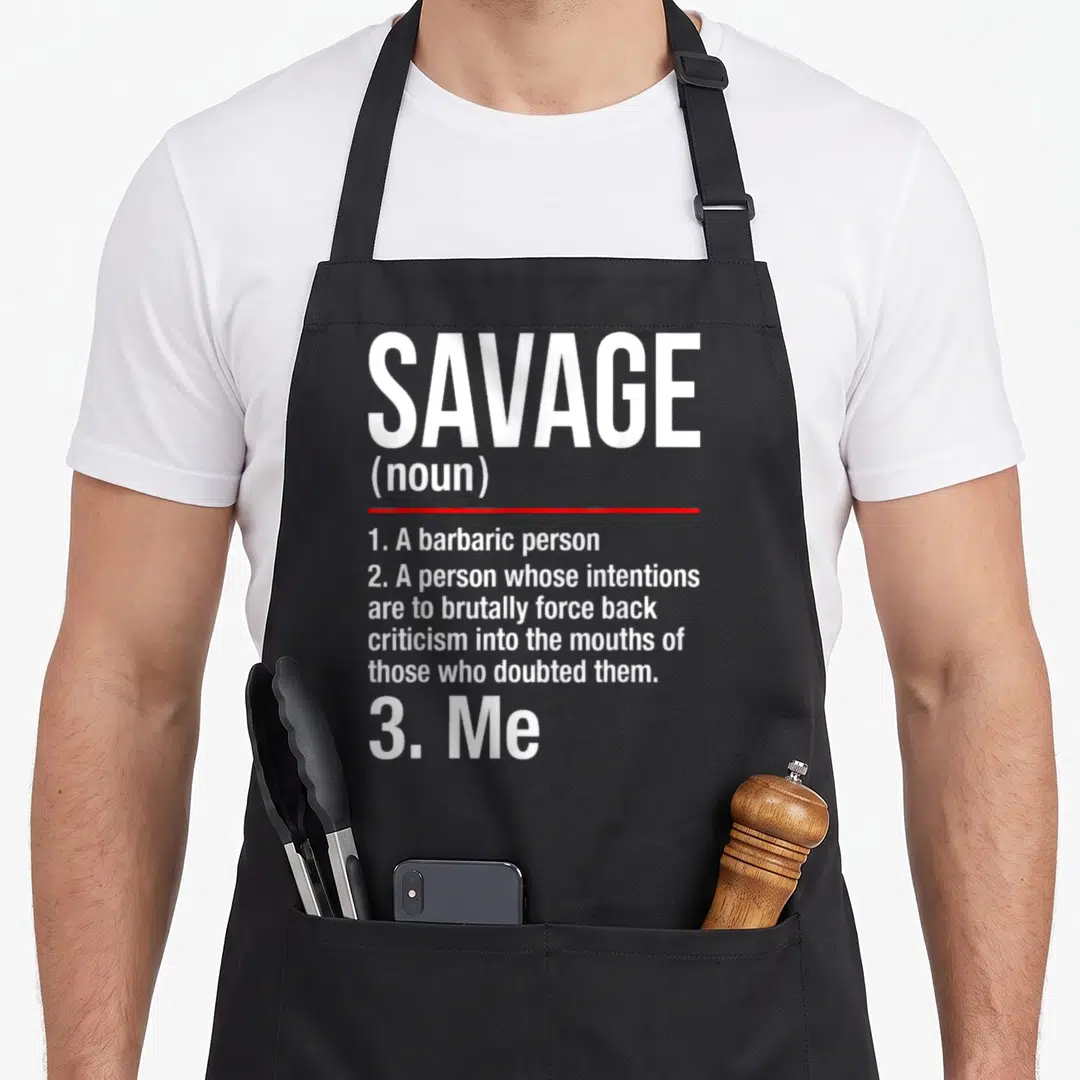 Funny savage apron - White dictionary text defining savage with a red underline and the word Me at the bottom — shown on a black cotton canvas apron against a white background