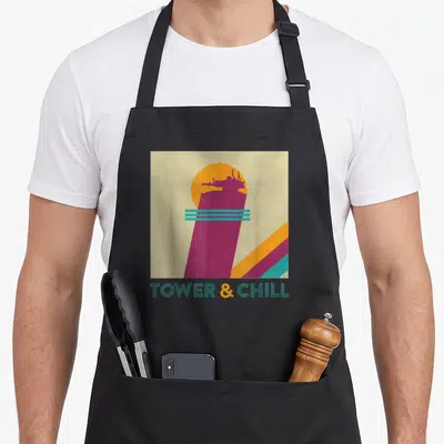 Tower hunter apron - Retro purple tower silhouette with teal lines and TOWER & CHILL text on beige background — shown on a black cotton canvas apron against a white background