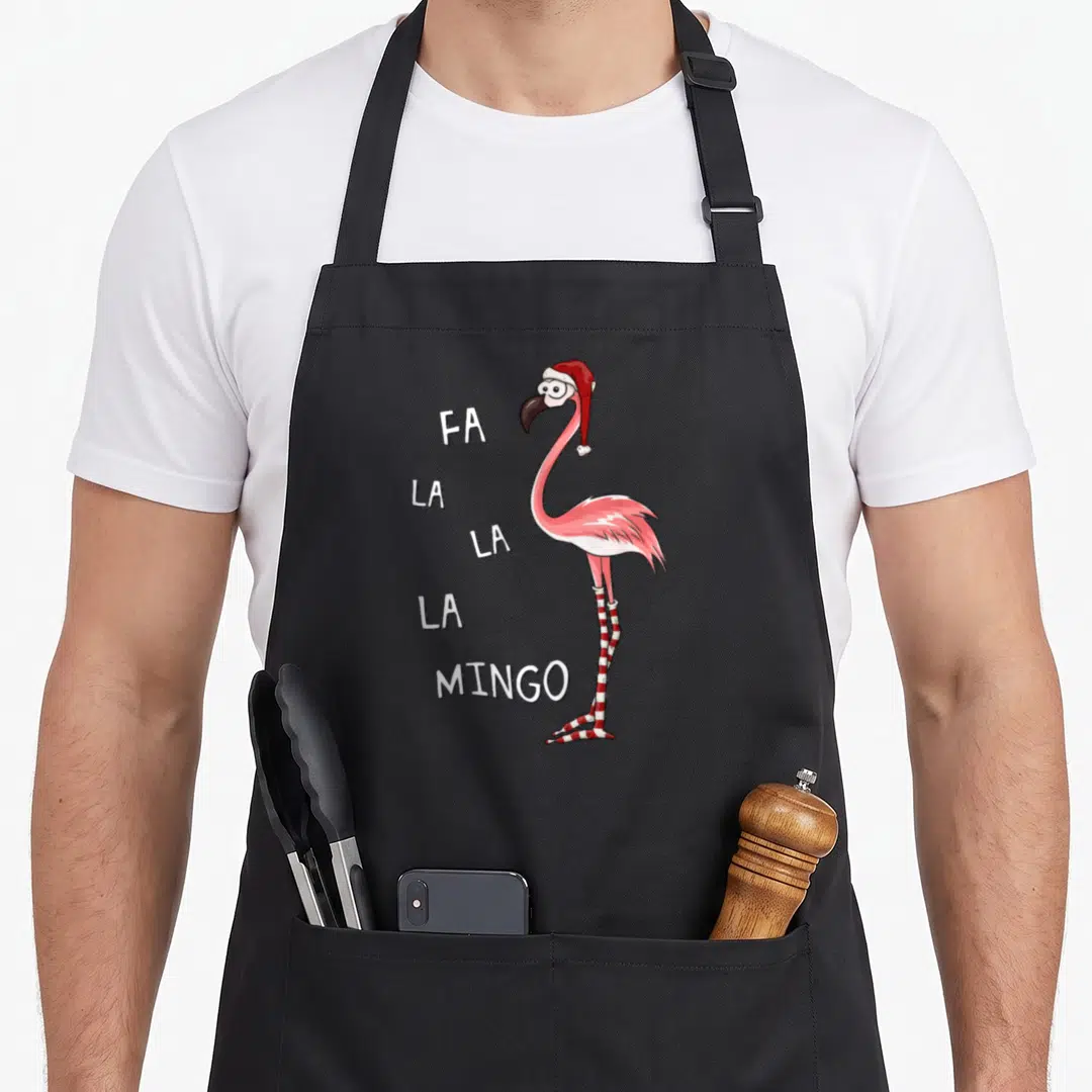 Stocking pink flamingo apron - Cartoon flamingo in Santa hat with striped legs and stacked FA LA LA LA MINGO text — shown on a black cotton canvas apron against a white background