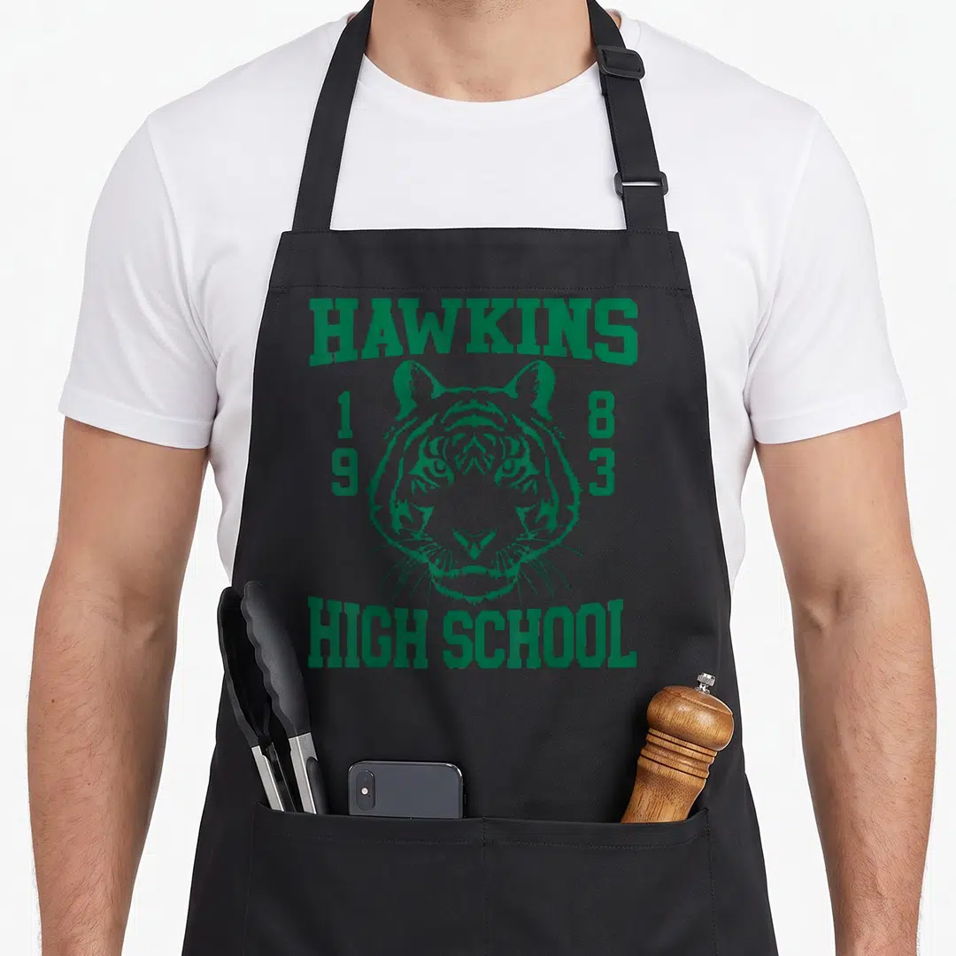 Hawkin novelty apron - Green line art tiger head with Hawkins High School 1983 text — shown on a black cotton canvas apron against a white background