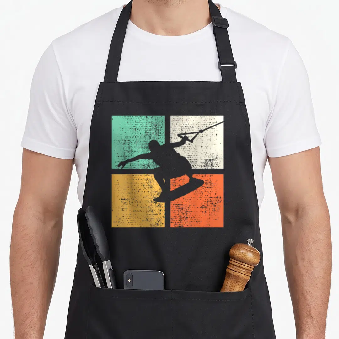 Wakeboard wakeboarder wakeboarding apron - Grey kitesurfer silhouette over teal beige yellow and orange textured squares — shown on a black cotton canvas apron against a white background