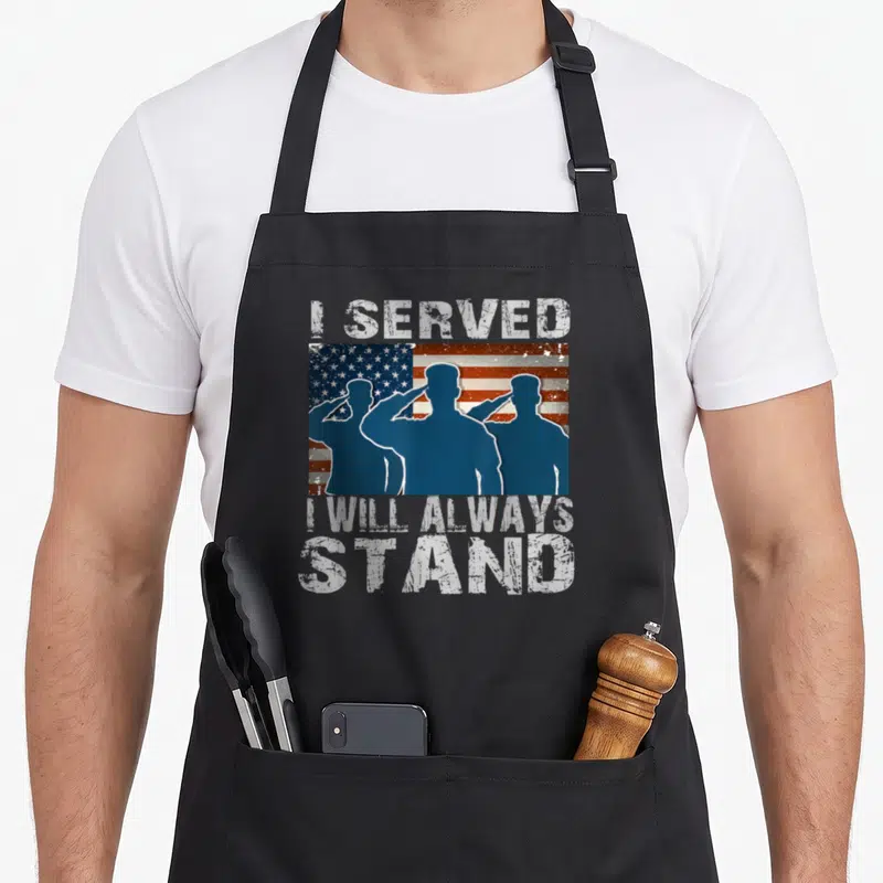 Alway patriotic apron - Distressed I Served I Will Always Stand text with three saluting soldiers on flag — shown on a black cotton canvas apron against a white background