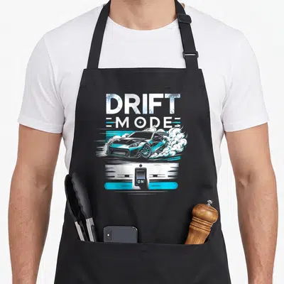 Mode car apron - Drift Mode ON text, blue grey drifting car, white smoke, toggle switch — shown on a black cotton canvas apron against a white background