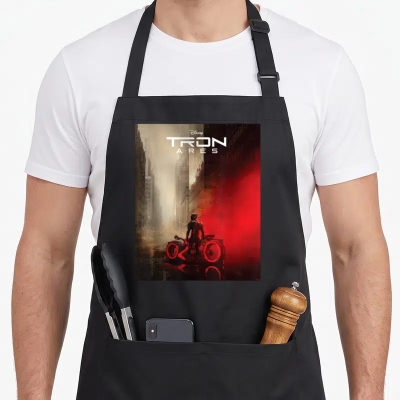 Tron movie poster apron - TRON ARES title text above person and light cycle in red grey city street scene — shown on a black cotton canvas apron against a white background