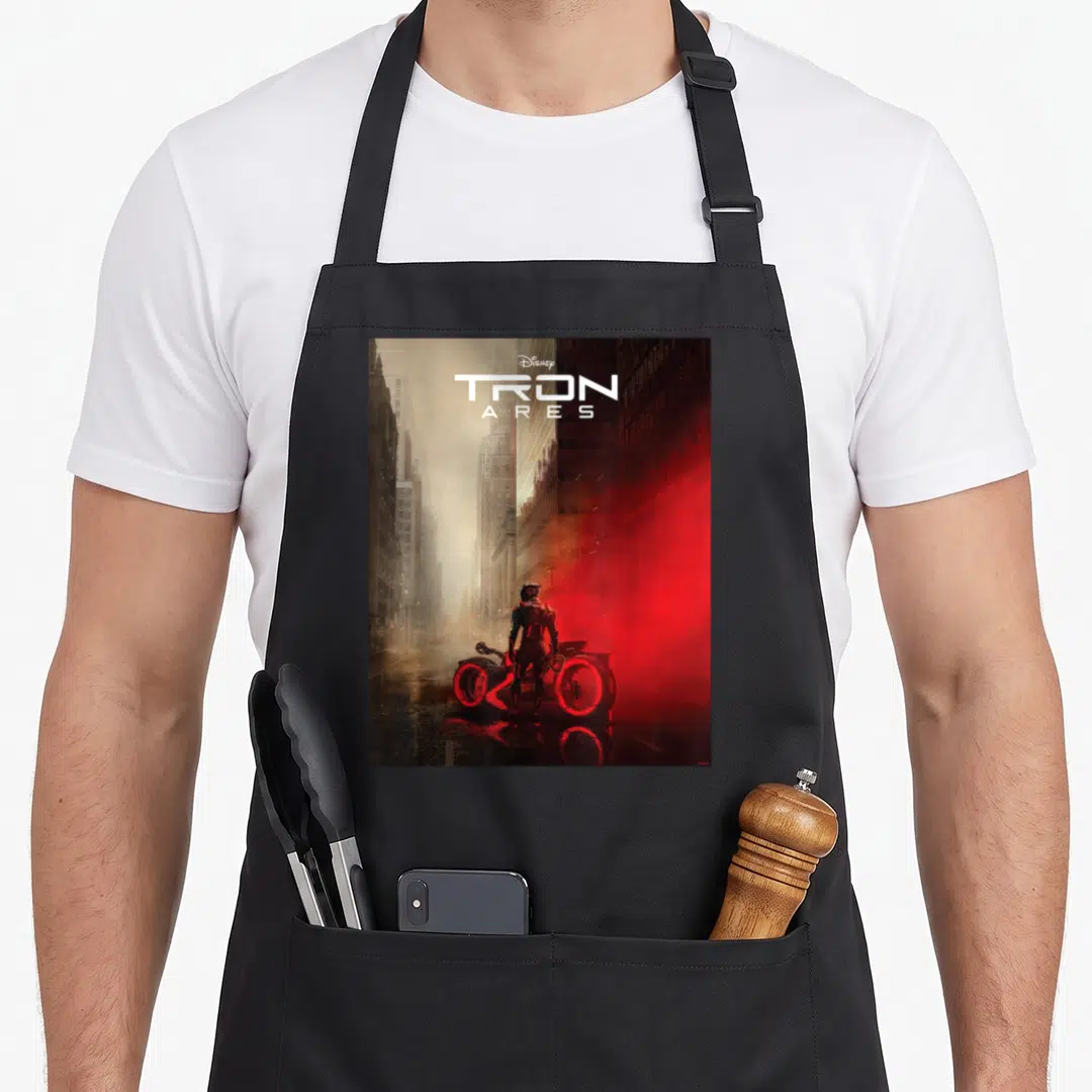 Tron movie poster apron - TRON ARES title text above person and light cycle in red grey city street scene — shown on a black cotton canvas apron against a white background
