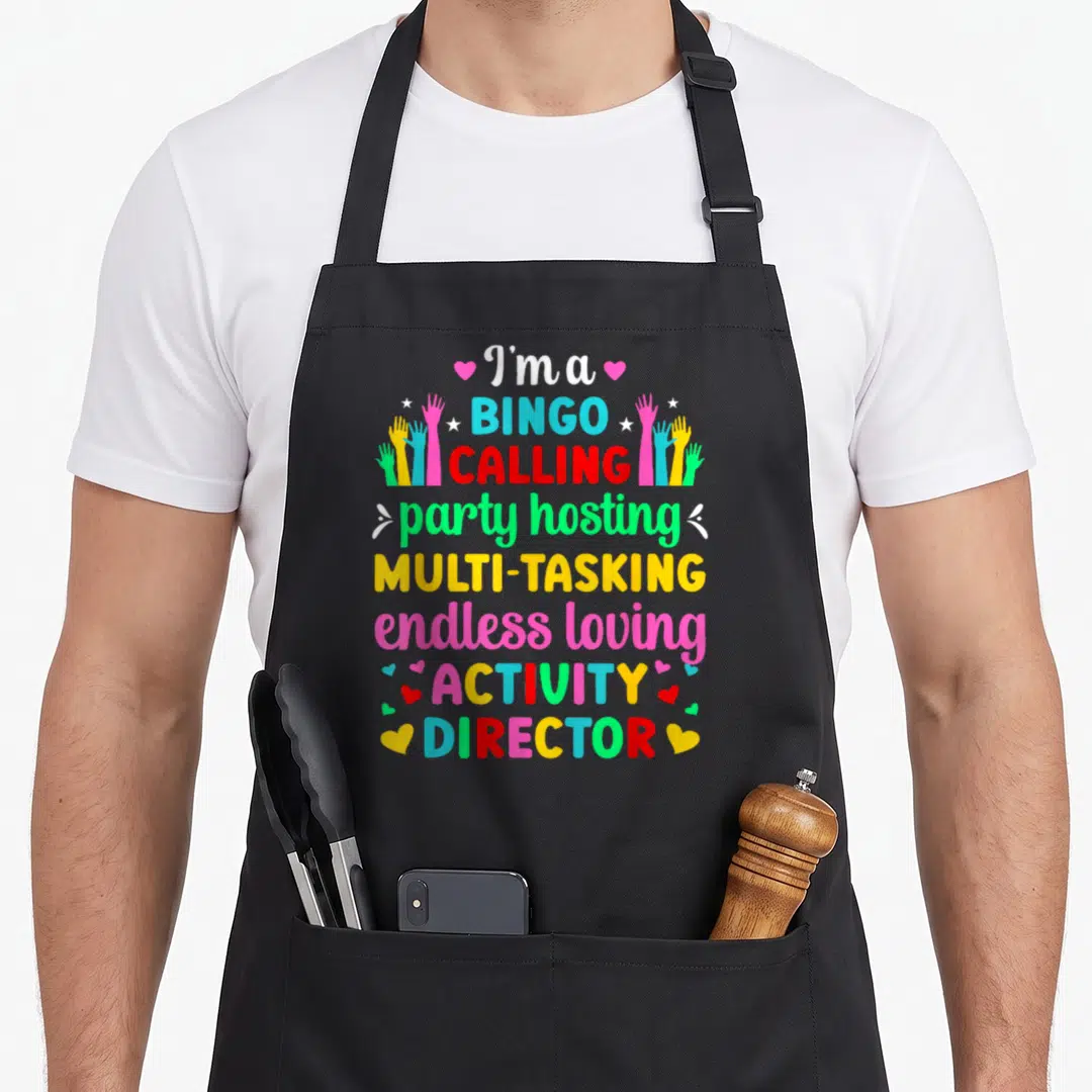 Coordinator activity apron - Stacked colorful text reading I'm a BINGO CALLING surrounded by raised hands and hearts — shown on a black cotton canvas apron against a white background