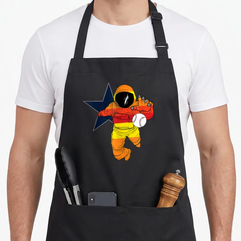Astronaut baseball apron - Cartoon astronaut in orange red and yellow stripes holding a white baseball in front — shown on a black cotton canvas apron against a white background