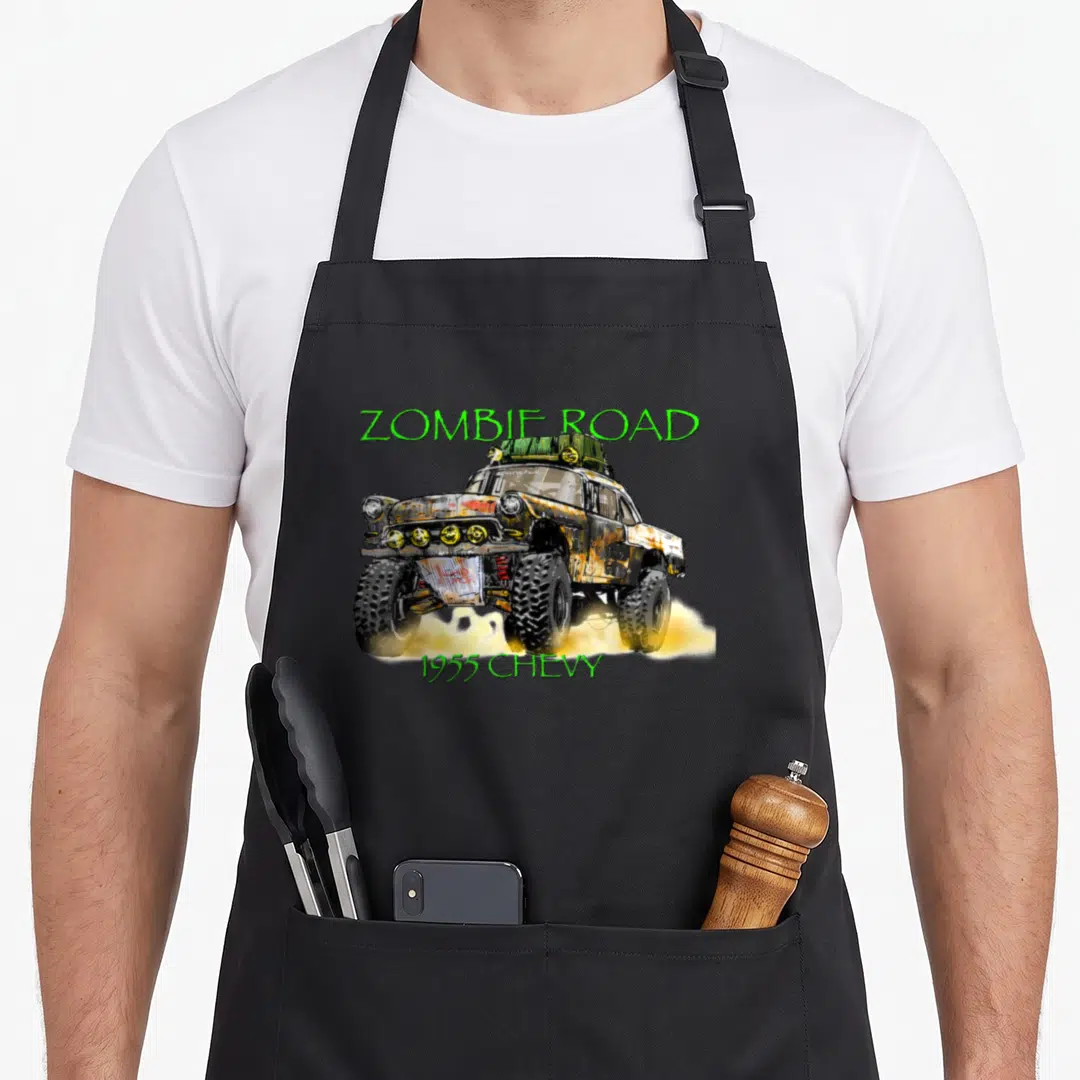 Zombie vehicle apron - Distressed 1955 Chevy truck on yellow smoke with green Zombie Road text — shown on a black cotton canvas apron against a white background
