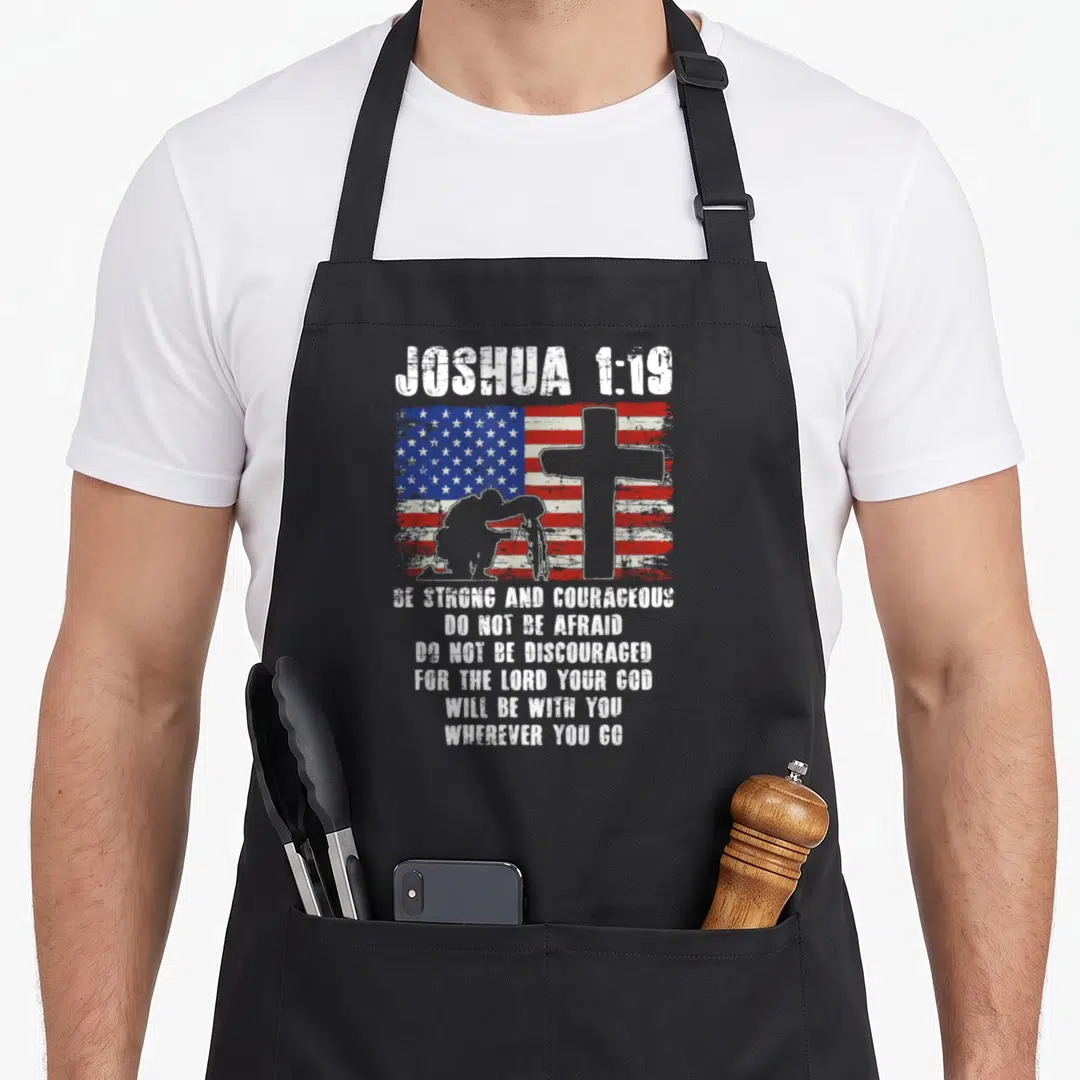 Patriotic bible verse apron - Joshua 1:19 text over distressed US flag, cross, and kneeling soldier silhouette in red — shown on a black cotton canvas apron against a white background