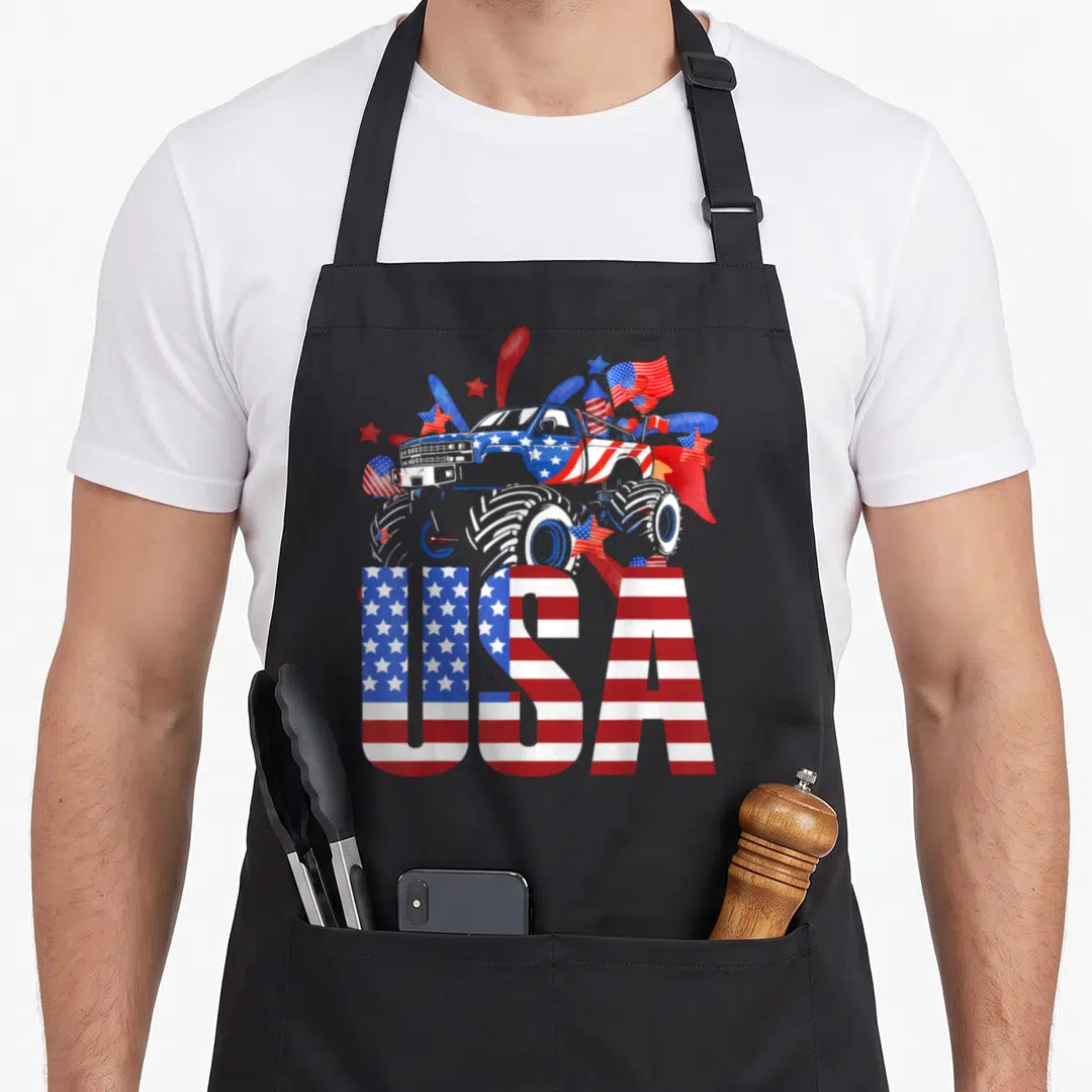 4th truck aprons - Monster truck with USA lettering filled with red white blue flag patterns and scattered stars — shown on a black cotton canvas apron against a white background