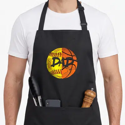 Basketball sports dad apron - Split yellow softball and orange basketball with grey DAD text in distressed style — shown on a black cotton canvas apron against a white background
