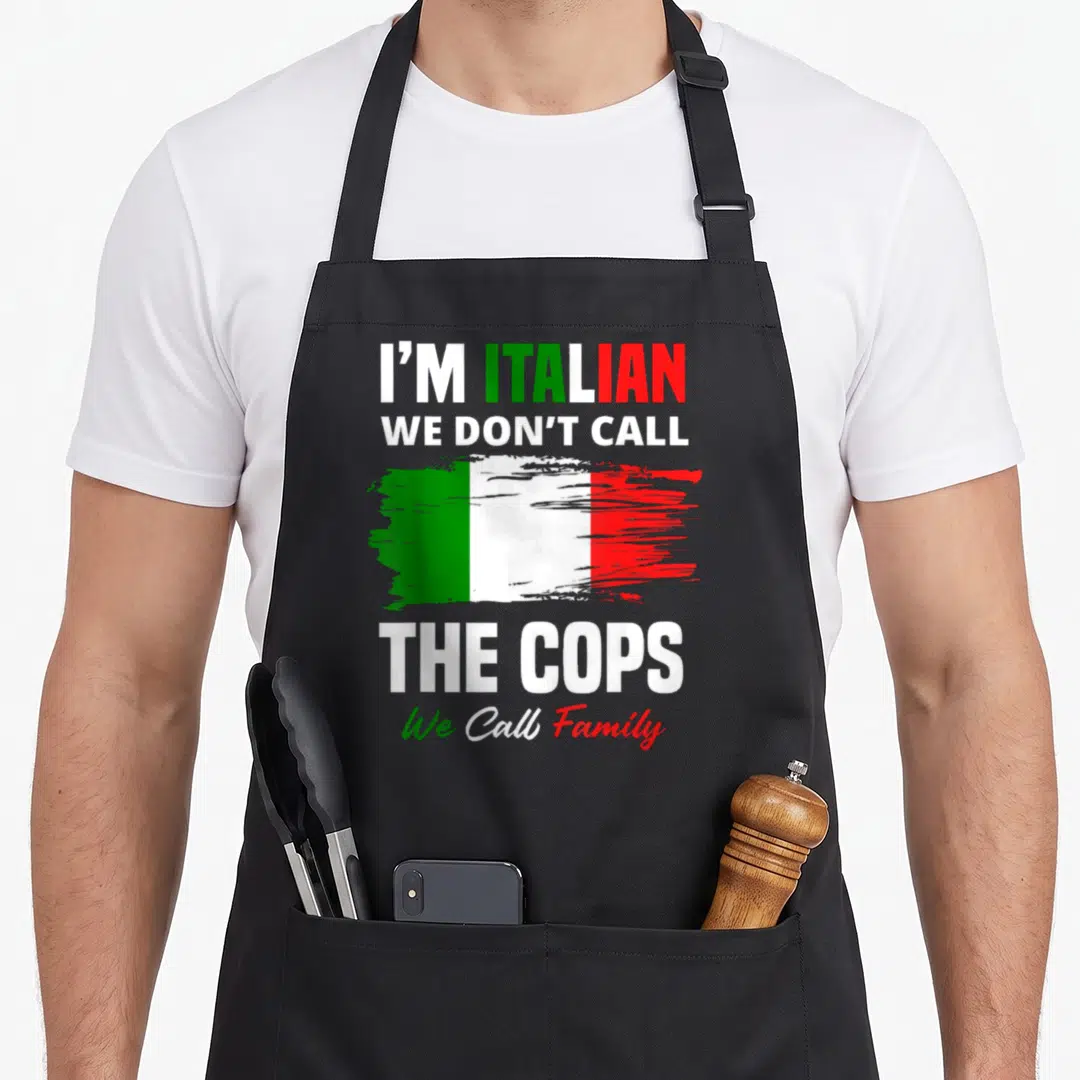 Family italy apron - I'M ITALIAN WE DON'T CALL THE COPS We Call Family text with green white red brush stroke flag — shown on a black cotton canvas apron against a white background