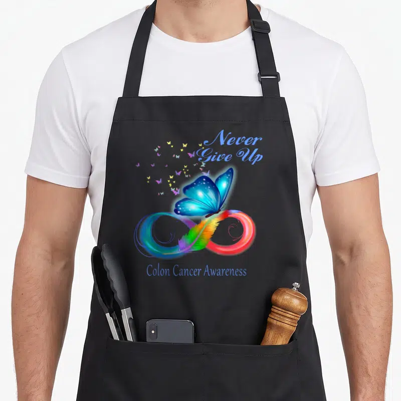 Cancer butterfly apron - Blue butterfly on rainbow feather infinity symbol with Never Give Up text — shown on a black cotton canvas apron against a white background