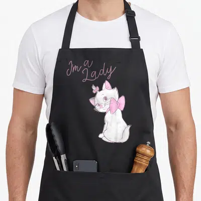 Aristocat marietta apron - I'm a Lady text above a white cat with pink bows in cartoon style — shown on a black cotton canvas apron against a white background