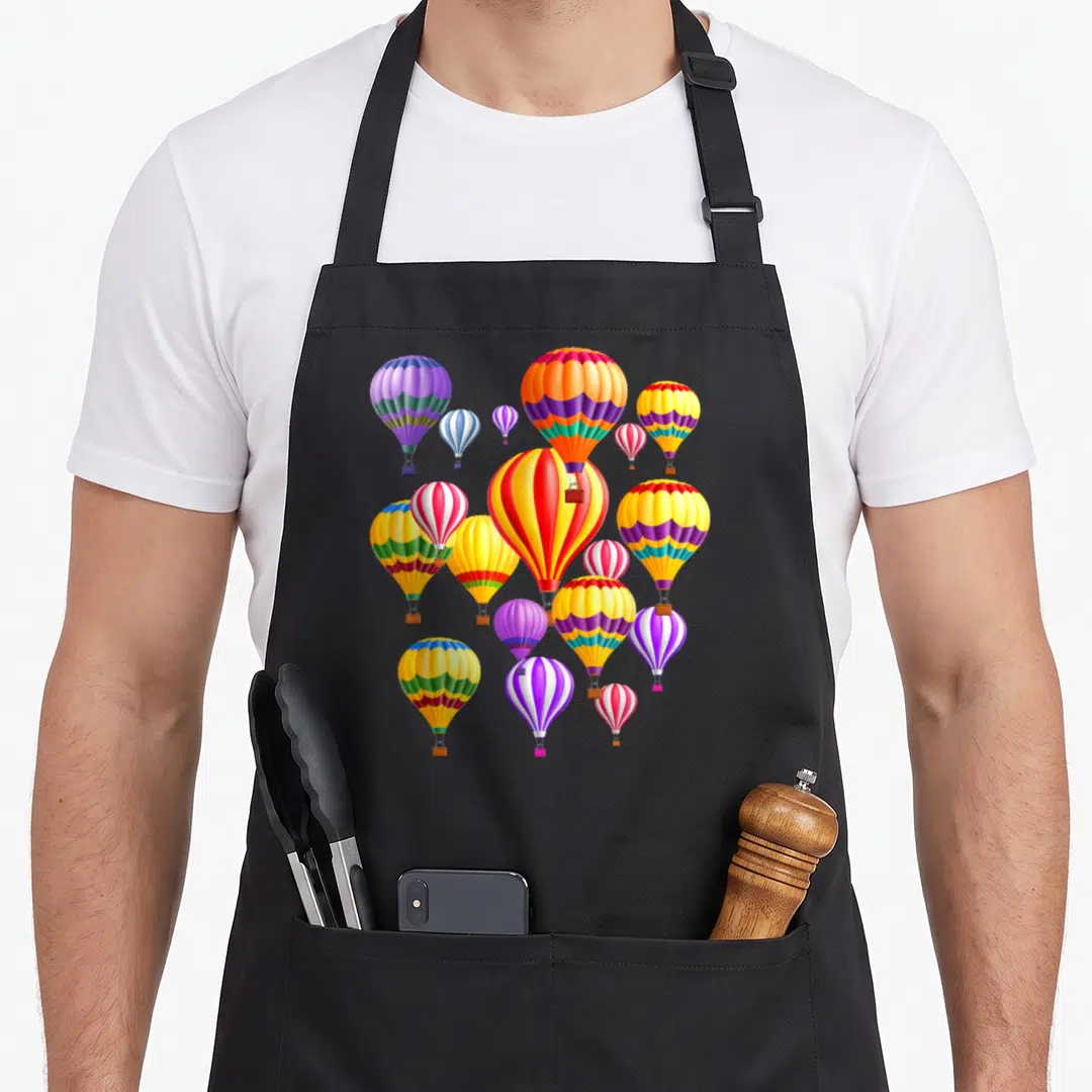 Colorful hot balloon apron - Cluster of cartoon hot air balloons in red, yellow, blue, purple, and green stripes — shown on a black cotton canvas apron against a white background