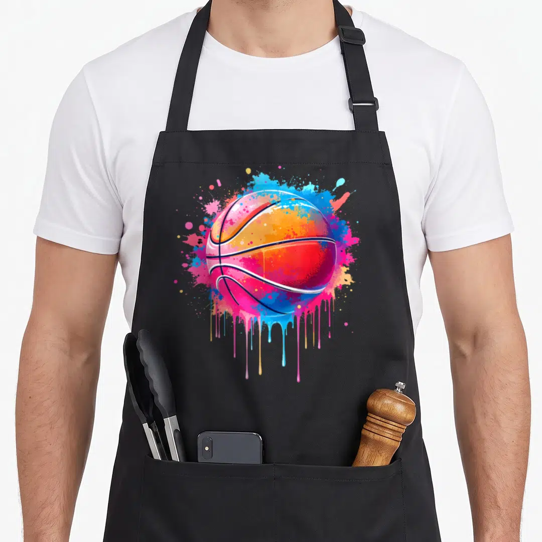 Basketball tie-dye apron - Multi-colored basketball with blue pink orange yellow paint splatters and dripping art — shown on a black cotton canvas apron against a white background