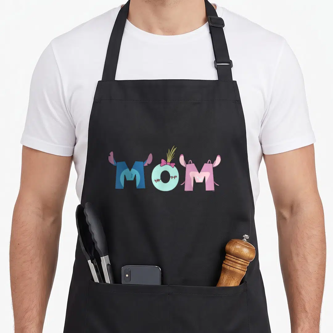 Family mother's day aprons - Cartoon MOM text with blue ears, stitched drink O, and pink ears in blue pink yellow — shown on a black cotton canvas apron against a white background