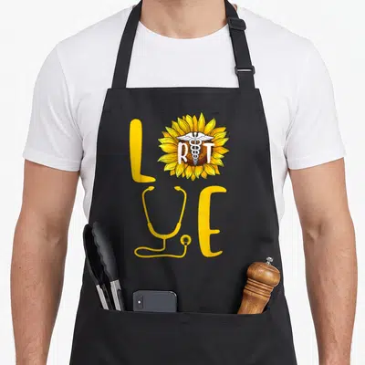 Sunflower nurse apron - LOVE text with sunflower containing RT and caduceus, yellow stethoscope replacing V — shown on a black cotton canvas apron against a white background