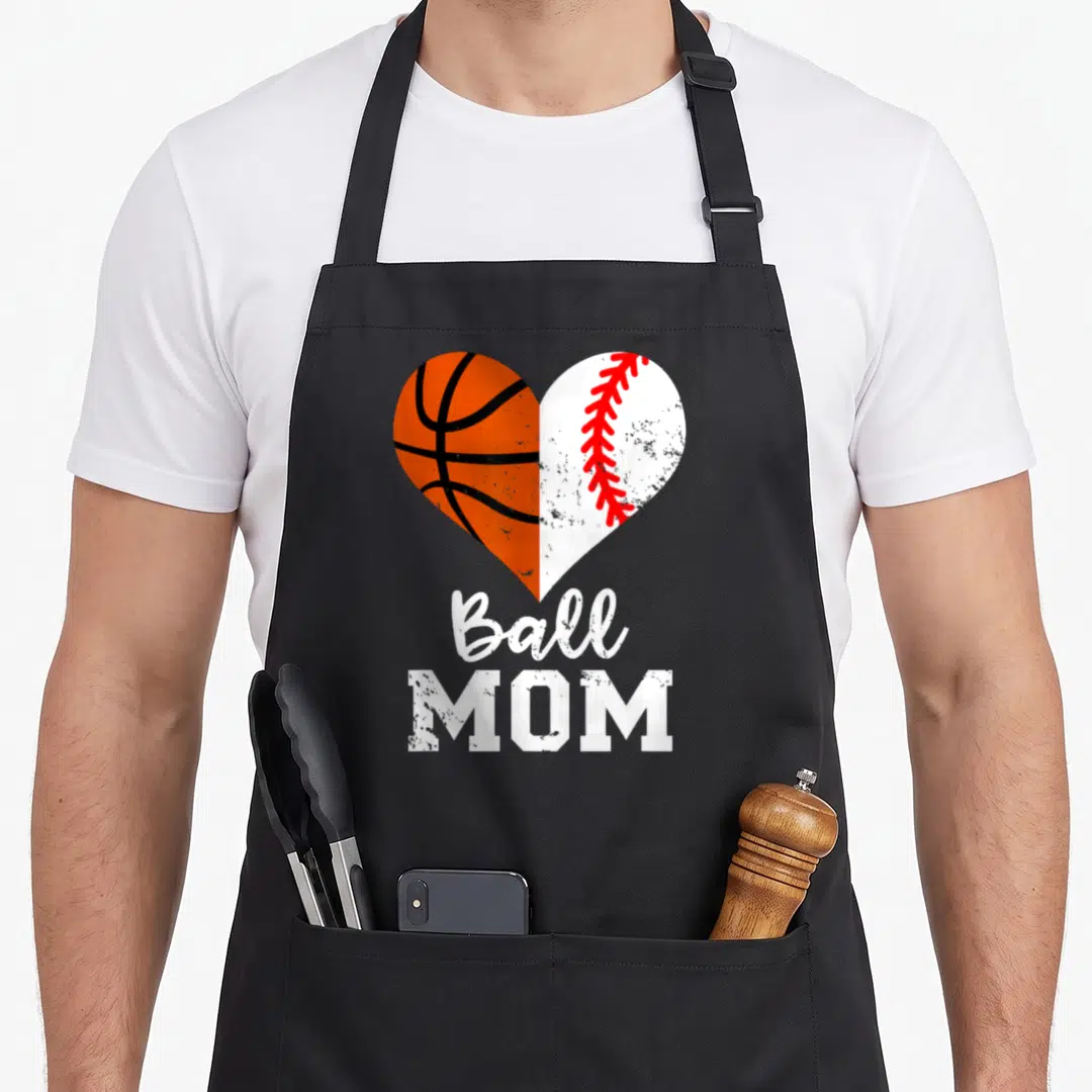 Basketball baseball apron - Split heart graphic with orange basketball left side and white baseball right side with red — shown on a black cotton canvas apron against a white background