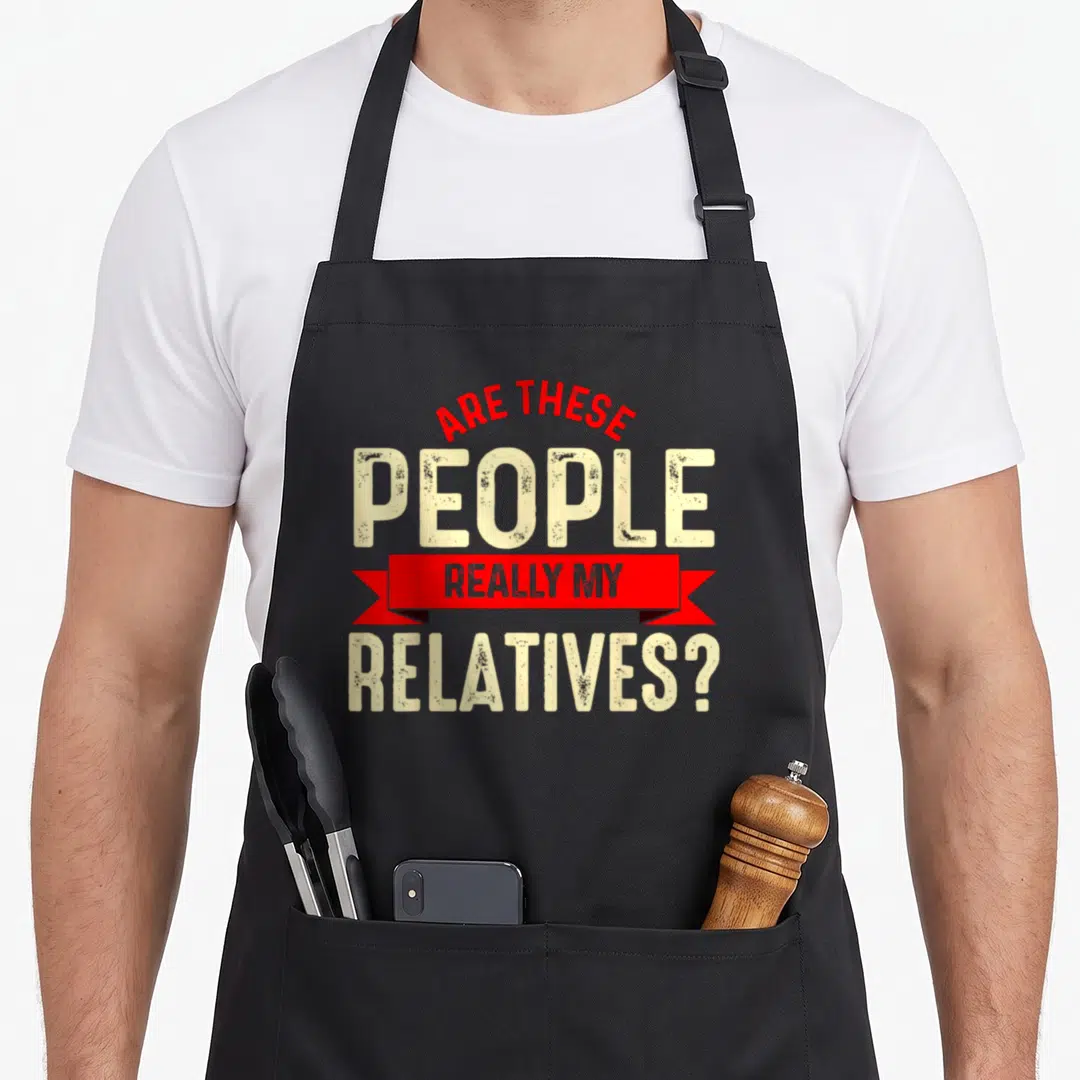 These family reunion aprons - Red ribbon banner with beige text reading Are These People Really My Relatives — shown on a black cotton canvas apron against a white background