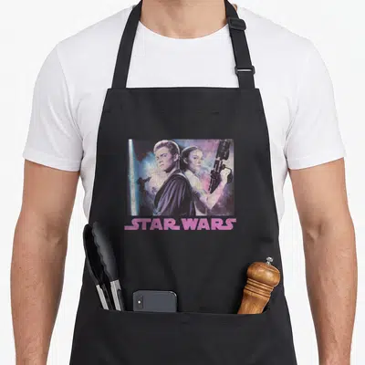 Annakin war apron - Photo of two characters with pink STAR WARS text below — shown on a black cotton canvas apron against a white background