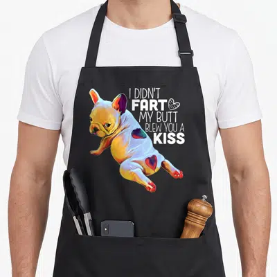 Bulldog french apron - Cartoon French Bulldog with hearts and text I Didn't Fart My Butt Blew You A Kiss — shown on a black cotton canvas apron against a white background