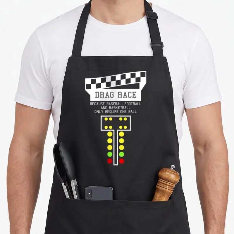 Drag christmas apron - Checkered flag, drag race text, and vertical light tree with yellow green and red lights — shown on a black cotton canvas apron against a white background