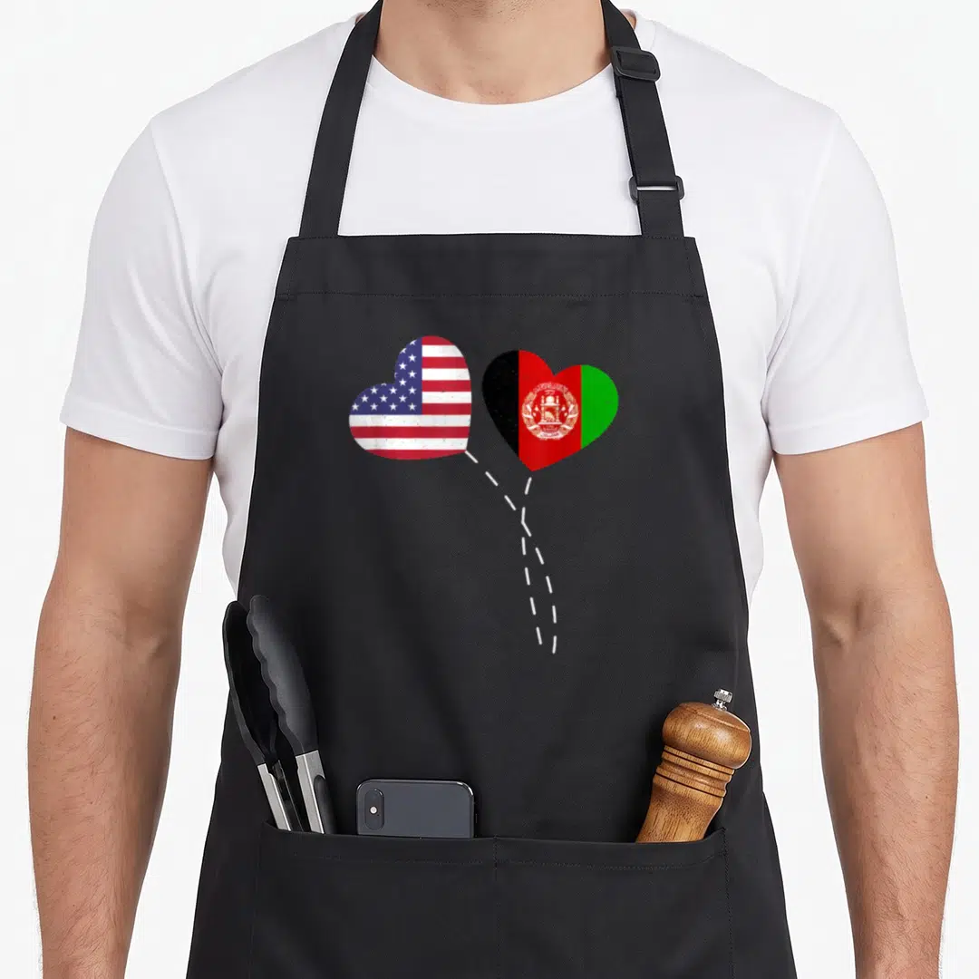 Loving afghanistan american flag apron - Two heart-shaped US and Afghan flags connected by a white dashed line — shown on a black cotton canvas apron against a white background