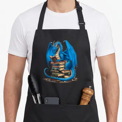 Reading dragon apron - Blue dragon perched on stacked books holding an open volume in realistic style — shown on a black cotton canvas apron against a white background