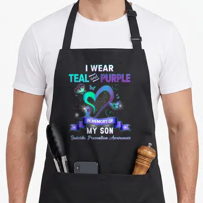 Awareness son suicide prevention apron - Heart ribbon and butterflies with I wear teal and purple in memory of my son — shown on a black cotton canvas apron against a white background