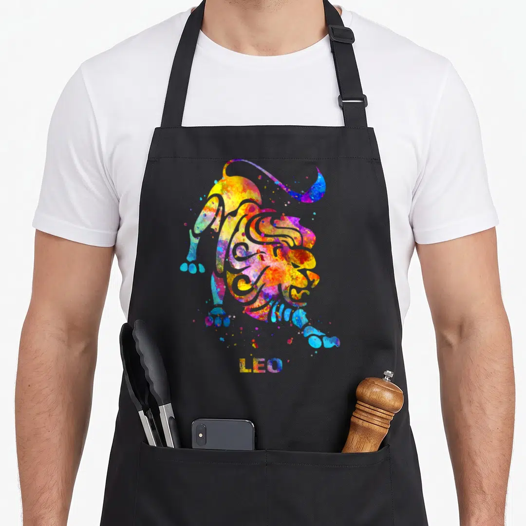 Leo sign zodiac aprons - Watercolor lion in yellow red blue purple with LEO text below — shown on a black cotton canvas apron against a white background