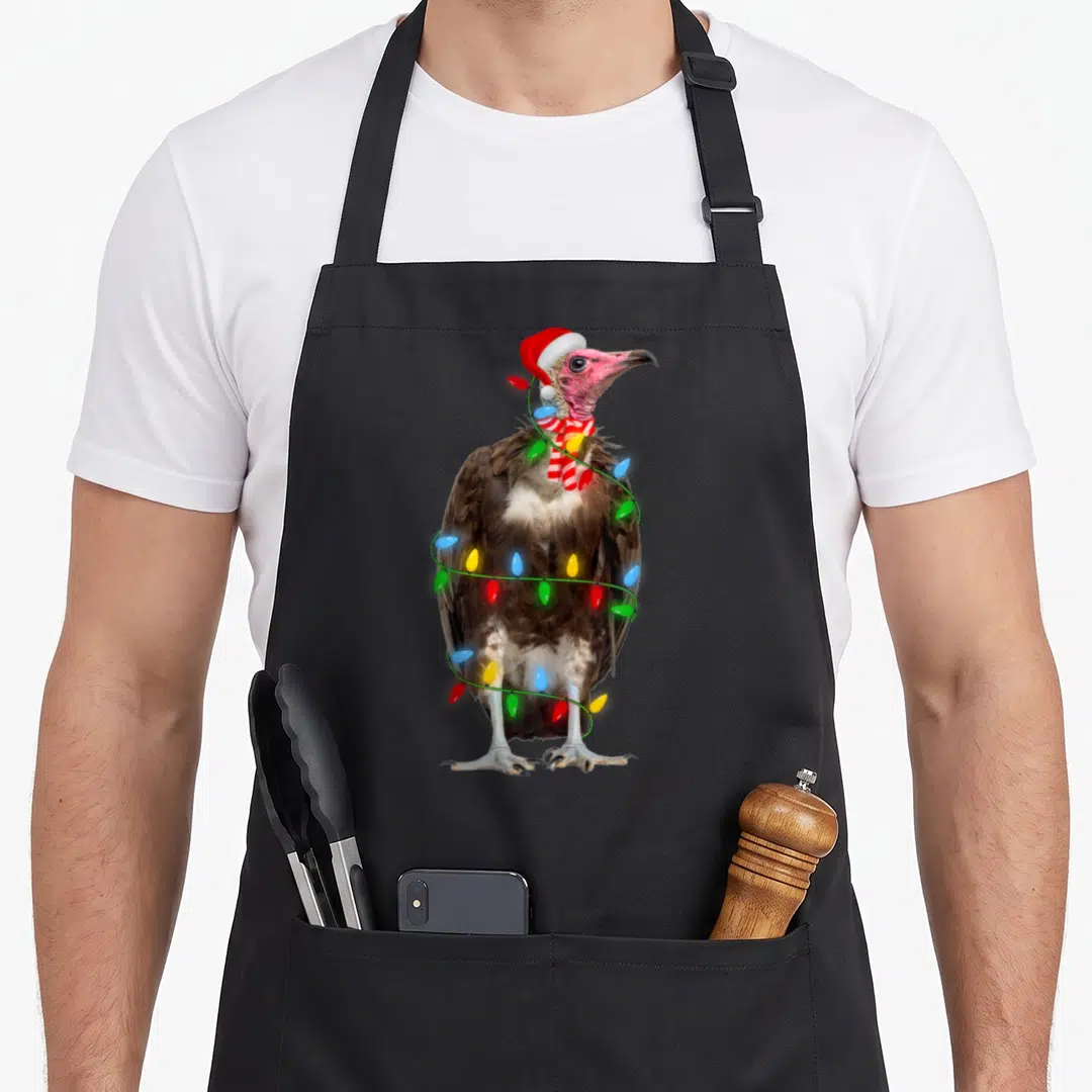 Vulture holiday christmas aprons - Standing vulture in Santa hat striped scarf wrapped in colorful Christmas lights — shown on a black cotton canvas apron against a white background