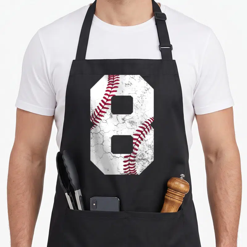 8th baseball apron - Large number 8 shaped like a baseball with red stitching on white textured background — shown on a black cotton canvas apron against a white background