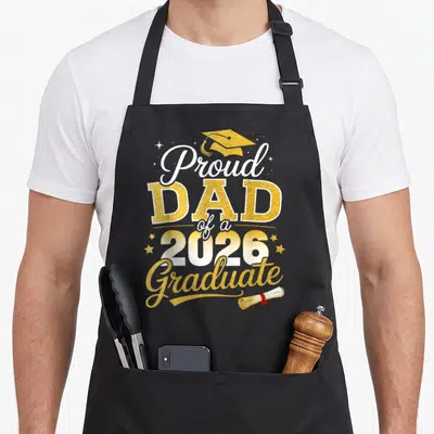 Class dad grad apron - Proud DAD 2026 Graduate text with gold cap and diploma scroll — shown on a black cotton canvas apron against a white background