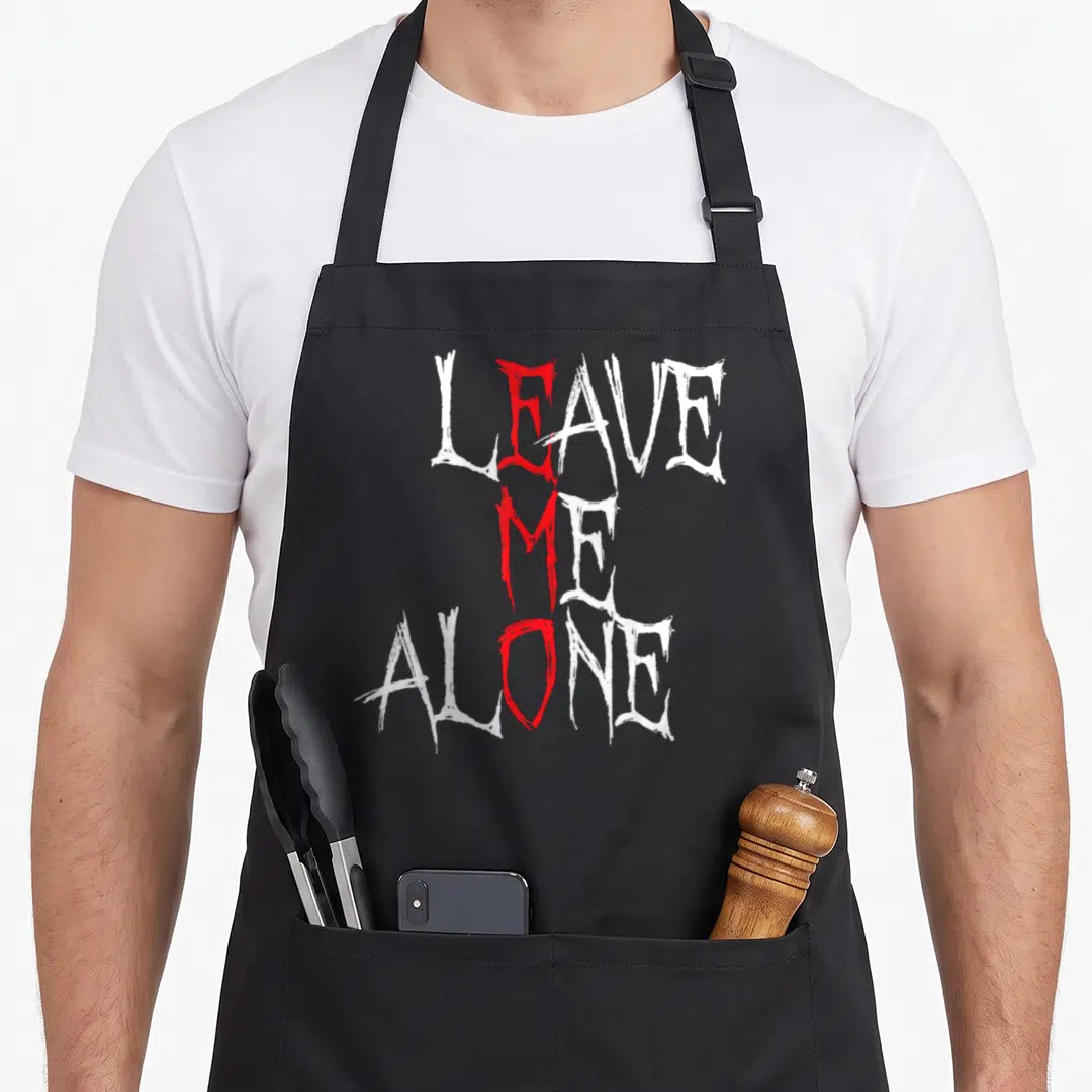 Leave goth apron - Distressed white and red text reading LEAVE ME ALONE with vertical red accent — shown on a black cotton canvas apron against a white background