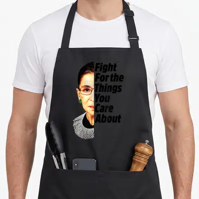 Ruth star quotes apron - Photo of RBG face next to vertical Fight For The Things You Care About text — shown on a black cotton canvas apron against a white background