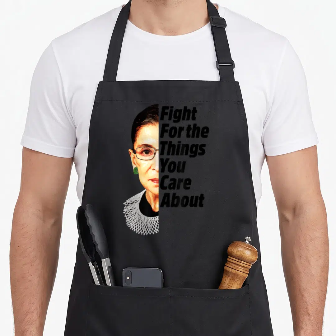 Ruth star quotes apron - Photo of RBG face next to vertical Fight For The Things You Care About text — shown on a black cotton canvas apron against a white background