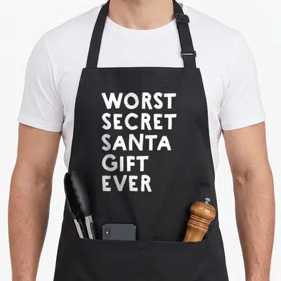 Worst elephant print apron - White stacked text reading WORST SECRET SANTA GIFT EVER — shown on a black cotton canvas apron against a white background