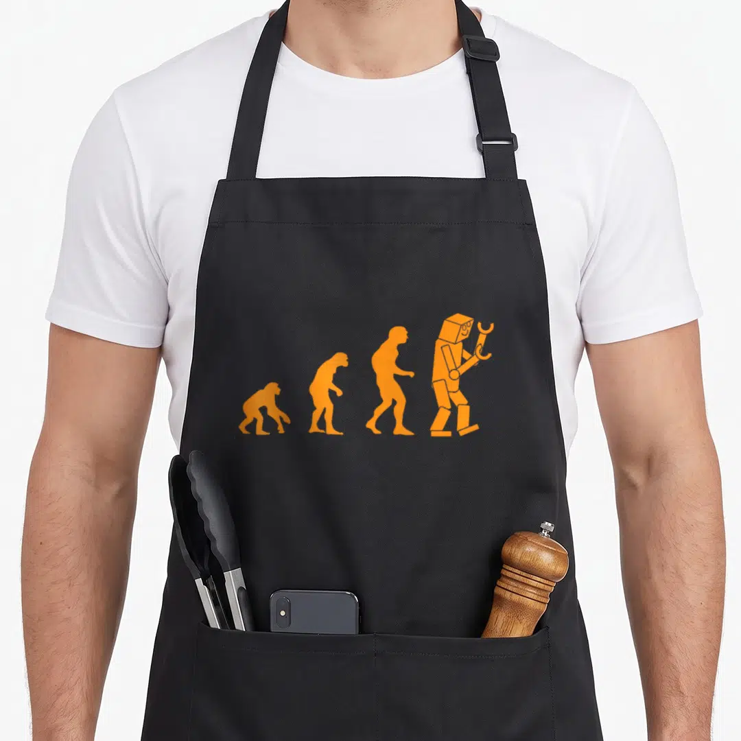 Robot nerdy apron - Four orange evolution silhouettes ending in a robot holding a wrench on black fabric — shown on a black cotton canvas apron against a white background