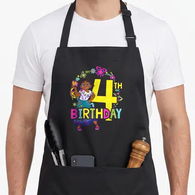 Mirabel floral aprons - Cartoon girl holding butterfly next to yellow 4TH BIRTHDAY text under a floral arch in pink — shown on a black cotton canvas apron against a white background